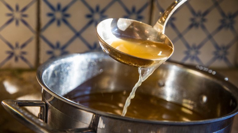 Ladle drizzling broth back into a soup pot