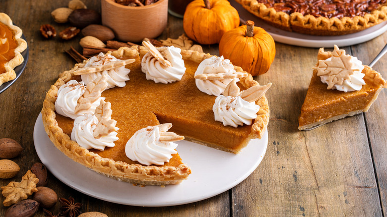 Classic pumpkin pie with whipped cream and pumpkin decor