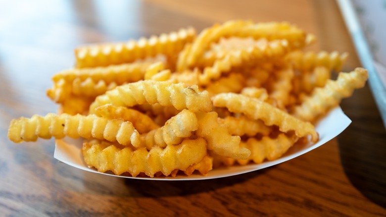 Shake Shack french fries in a paper container on a wooden table