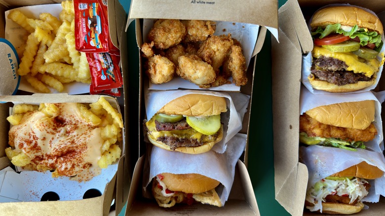 Shake Shack burgers, fries, sandwiches, and chicken nuggets in paper containers