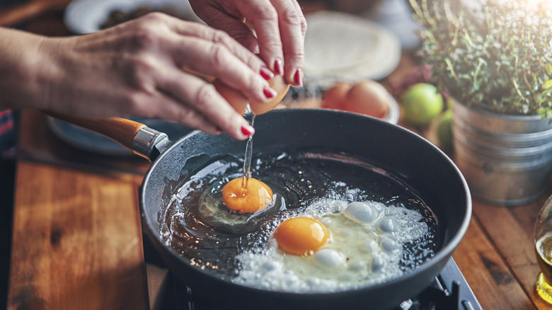 cracking eggs in a frying pan