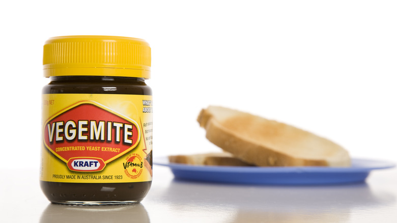 A jar of Vegemite beside plain toast.