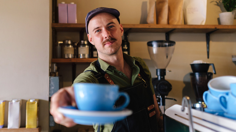 POV: a barista hands you a latte in a cafe.