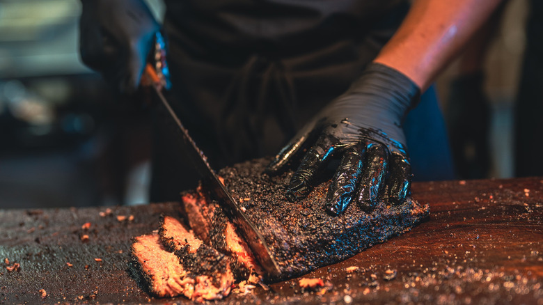 Hands slicing barbecued brisket