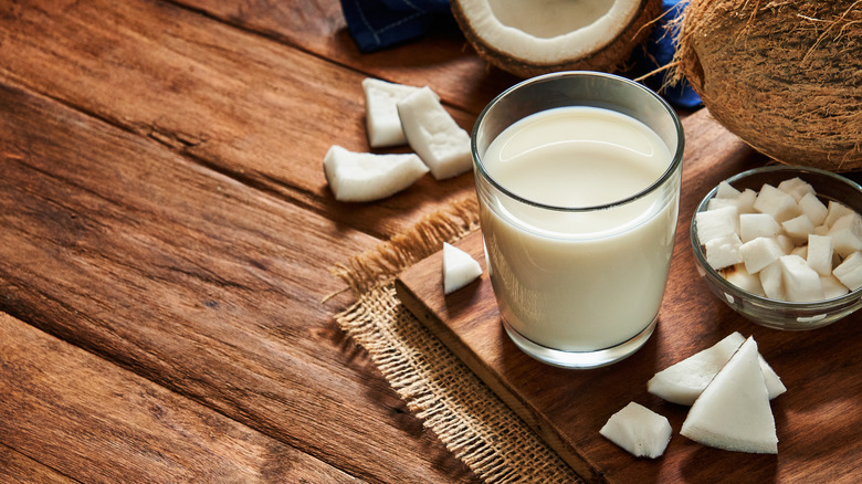 Glass of coconut milk next to bowl of coconut chunks