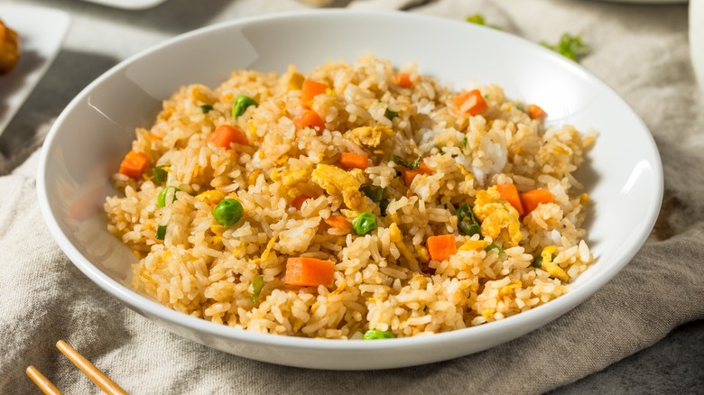 Vegetable fried rice in a white bowl with chopsticks