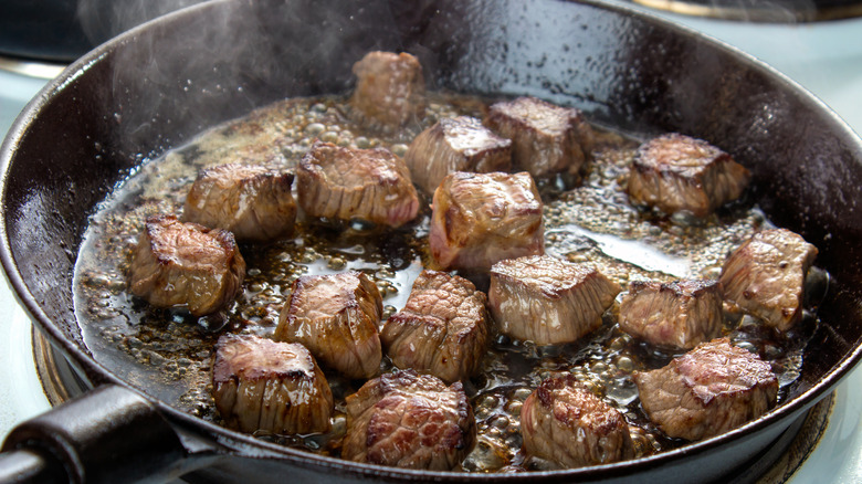 Beef chunks cooking in pan