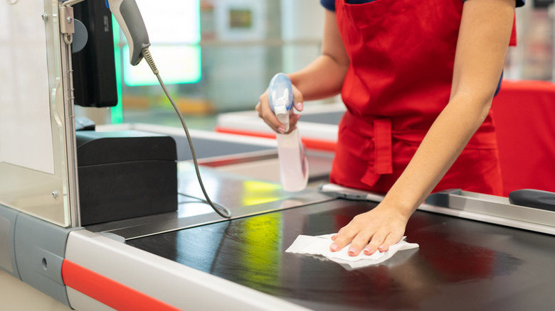 Cashier wiping down conveyer belt