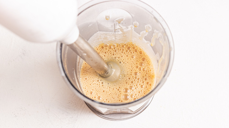 Immersion blender in a container with creamy liquid