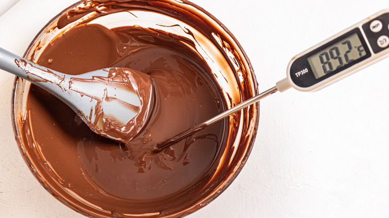 Tempered chocolate in a bowl with a whisk and a thermometer