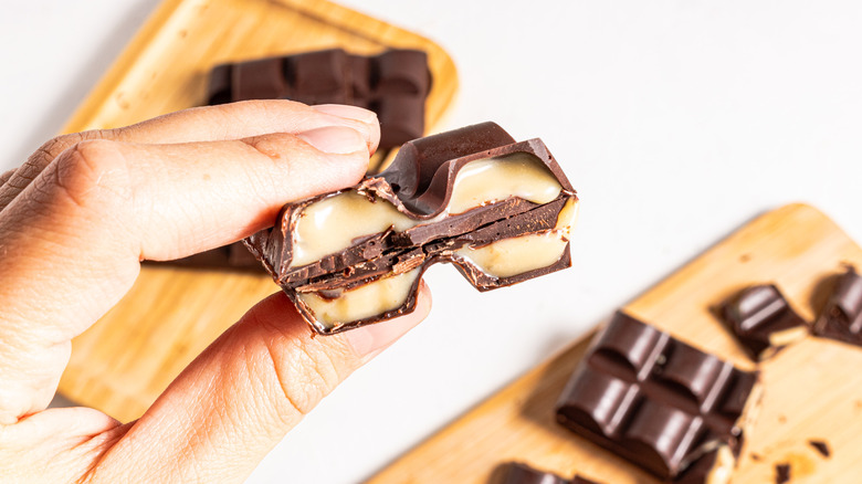 Holding two haves of Baileys Irish cream-stuffed chocolate bar showing the filling