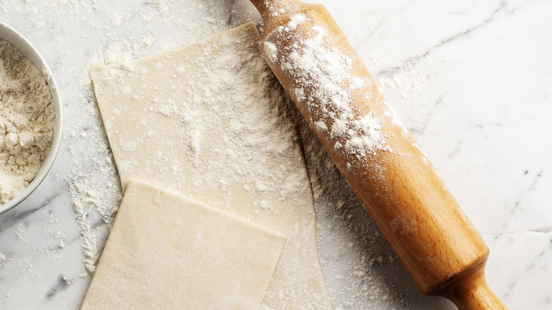 Puff pastry sheets with flour and a rolling pin