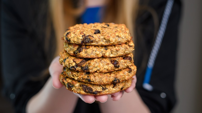 Hands holding oatmeal raisin cookies