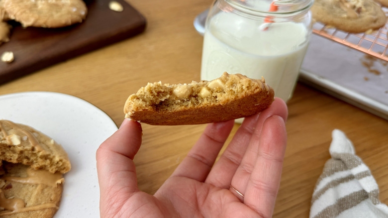 Hand holding a peanut butter cookie with a bite taken out