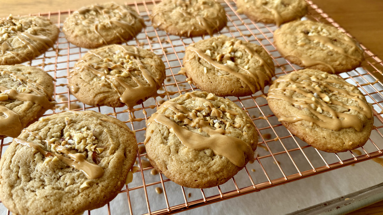 Peanut butter cookies topped with peanut butter drizzle on a wire rack