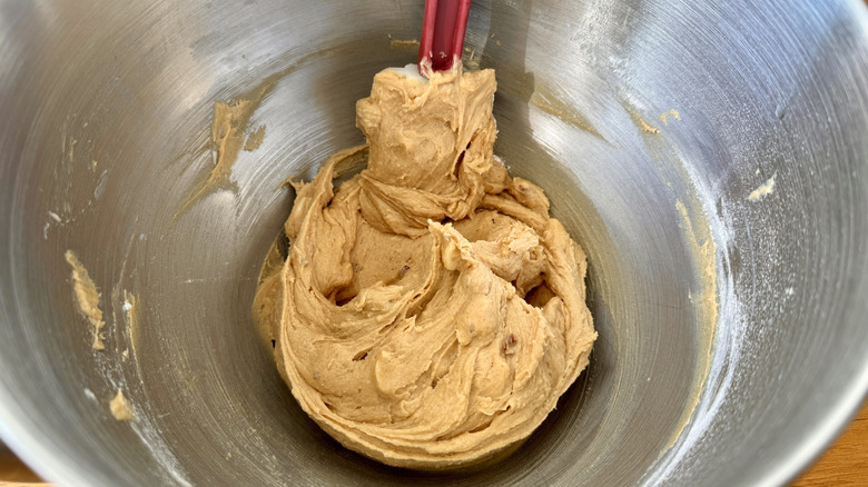 Cookie dough with a rubber spatula in a metal bowl