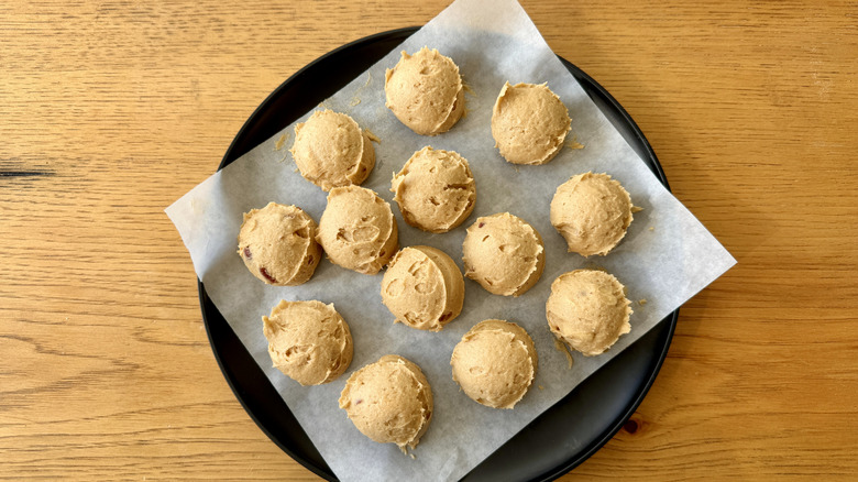 Scooped peanut butter cookie dough on a parchment-lined plate