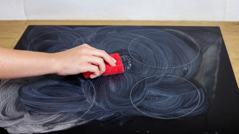 cleaning stovetop with sponge