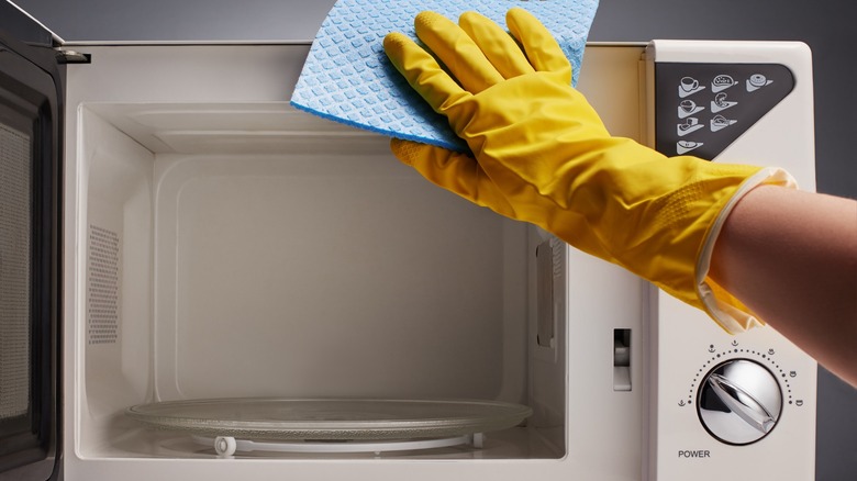 Gloved hand cleaning open microwave