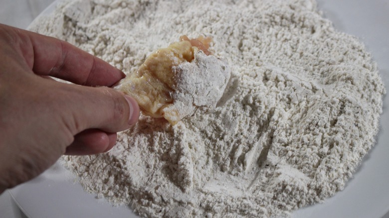 dredging chicken wing in flour