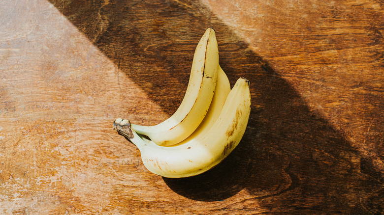 Three bananas on a wooden table