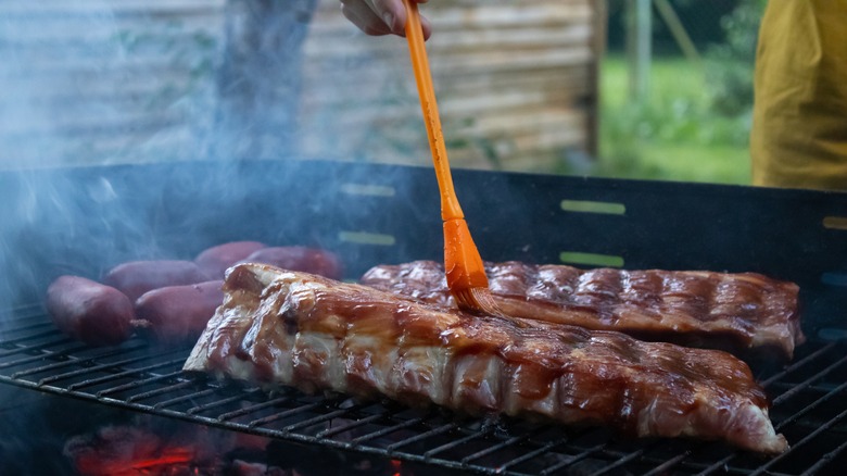 brushing barbecue sauce on ribs