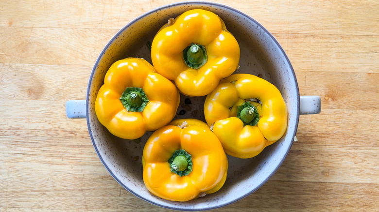 Barley and walnut-stuffed bell peppers in baking dish with pepper tops