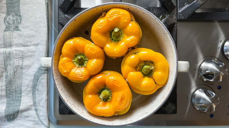 Barley and walnut-stuffed bell peppers in baking dish on stovetop