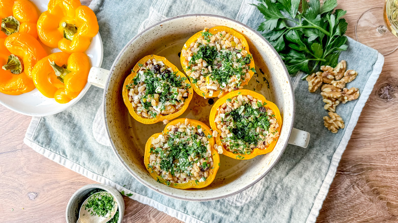 Barley and walnut-stuffed peppers in baking dish with parsley garnish