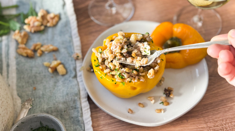 Barley and walnut-stuffed bell pepper with fork lifting filling on plate