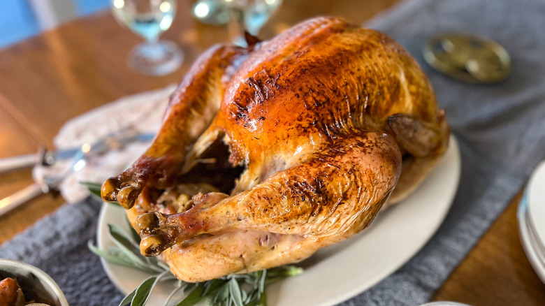 Basic roasted turkey on platter on table with herbs
