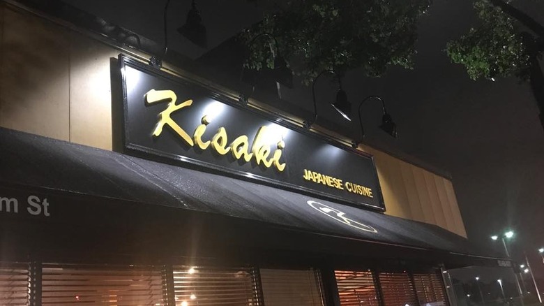 Sign reading "Kisaki Japanese Cuisine" in yellow font on a black background on outside of building