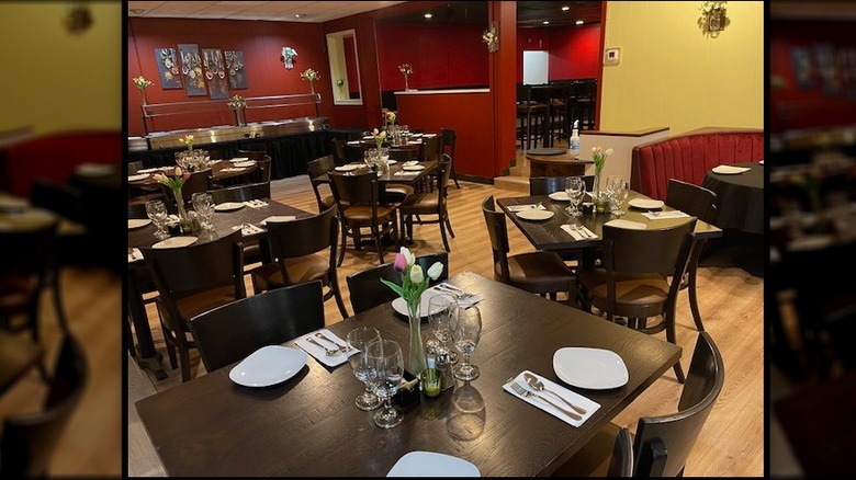 Dining room inside Taste of Mumbai, with yellow and red walls, light wood floors, and dark wood tables and chairs