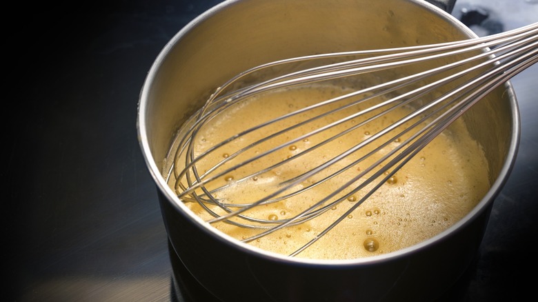 Cooking beurre blanc sauce in pan with whisk