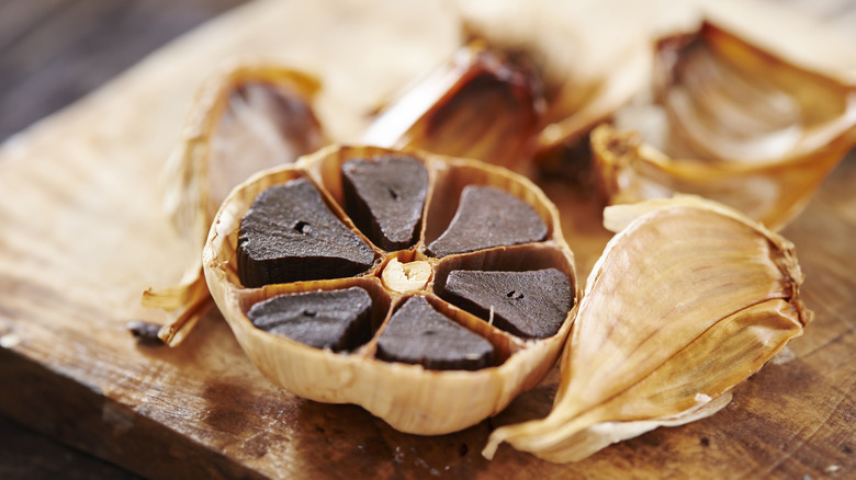 Black garlic chopped open on a wooden board.