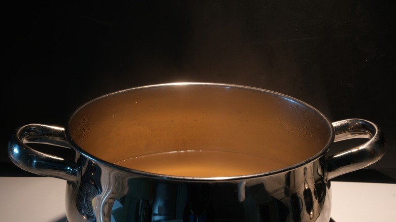 metal pot on stove filled with a brown broth