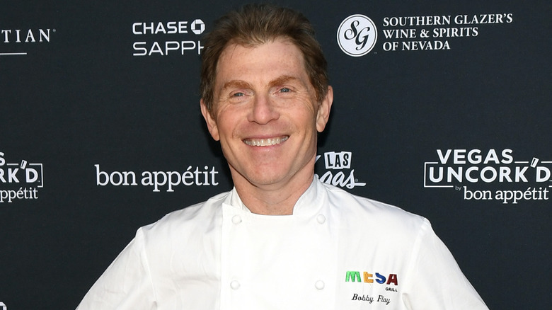 Bobby Flay smiling and wearing a white chef jacket