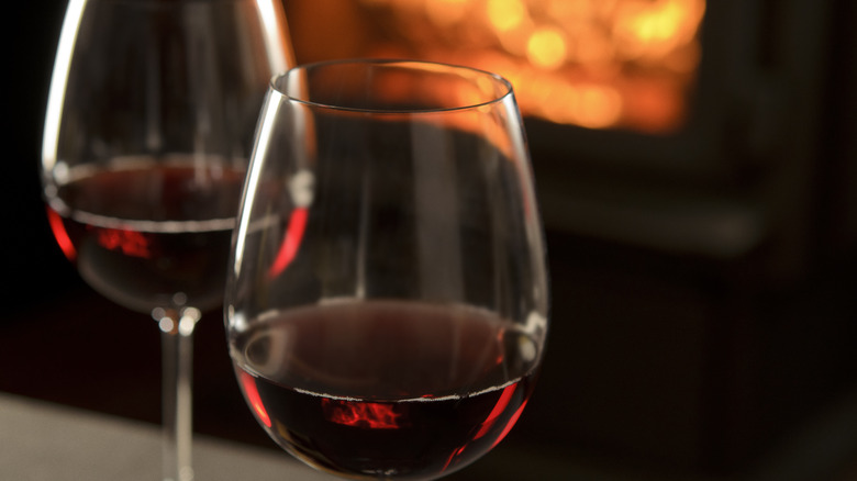 Glasses of red wine with a fireplace in the background