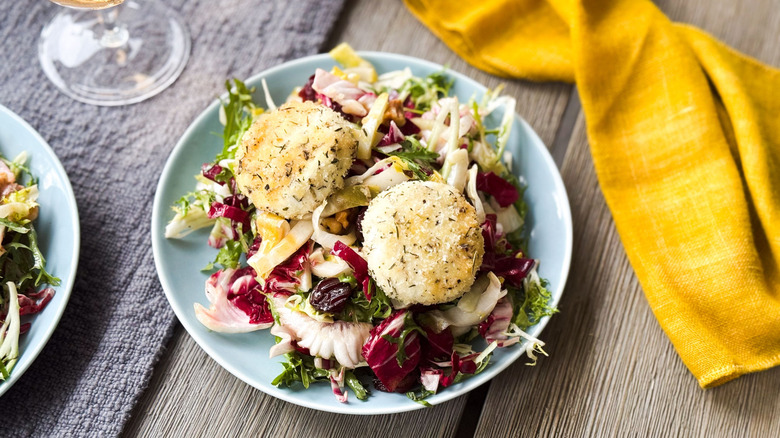 Breaded and baked goat cheese salad on plate with napkin