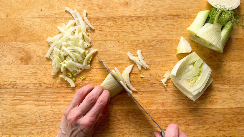 Thinly slicing fennel bulb on cutting board