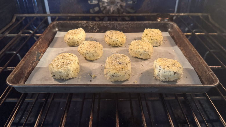 Breaded goat cheese rounds baking in oven on baking sheet