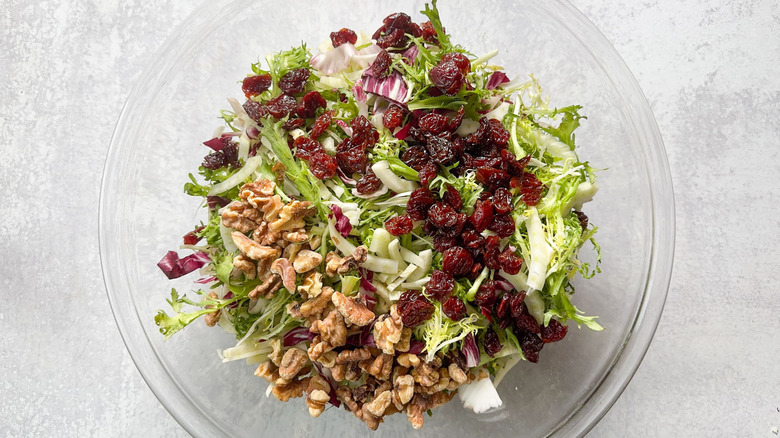 Salad greens with dried cherries and walnuts in large glass bowl