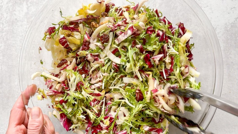 Tossing salad greens with toasted walnuts and dried cherries
