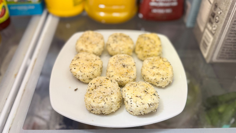 Breaded goat cheese rounds on plate in refrigerator