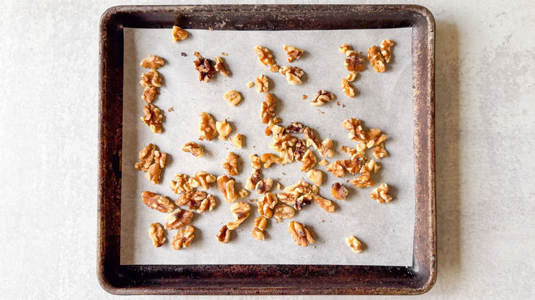 Walnuts halves and pieces on parchment-lined baking sheet