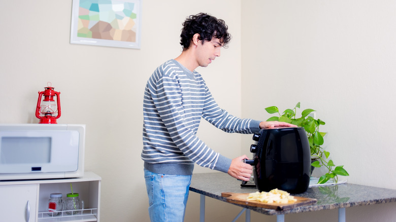 Person in striped shirt opening air fryer basket