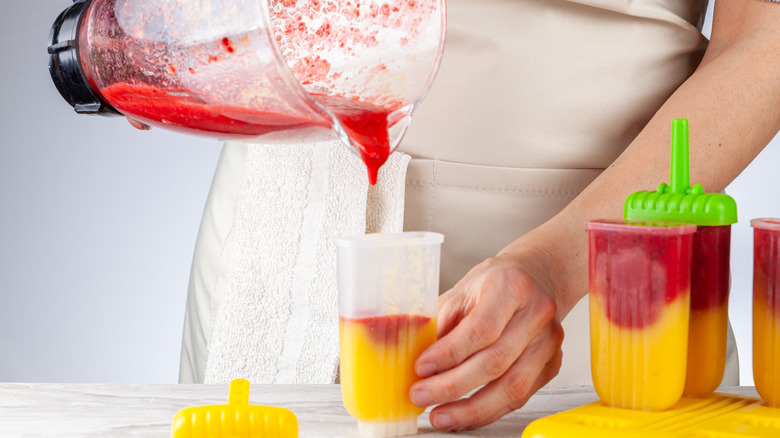 Hands pouring blended food into mold