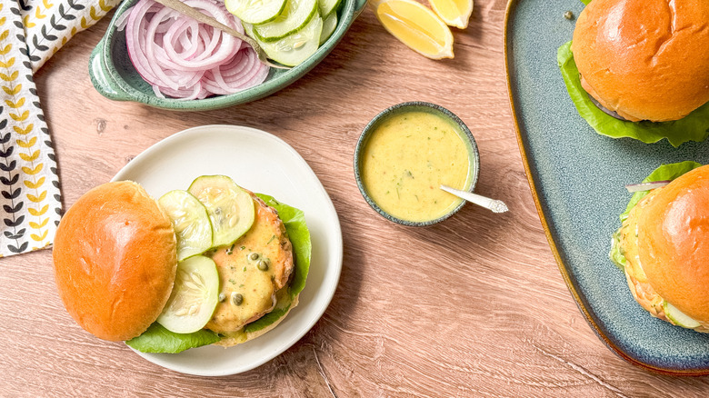 Broiled salmon burgers with curry remoulade and garnishes served on table