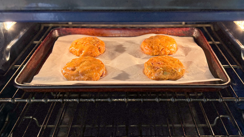 Salmon burgers on baking sheet under broiler