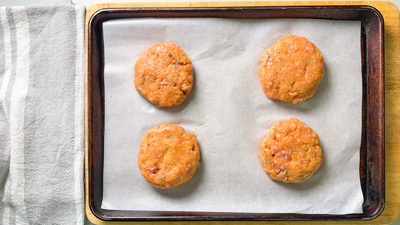 Salmon patties on parchment paper on baking sheet